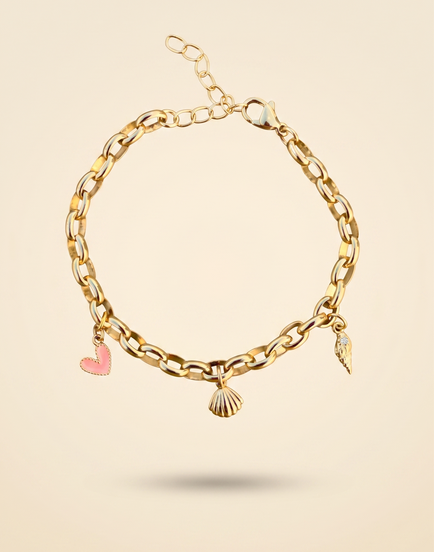 Gold chain bracelet with heart and shell charms on a beige background