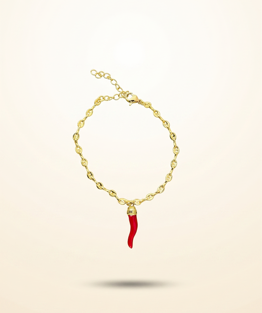 Gold bracelet with a red charm on a beige background