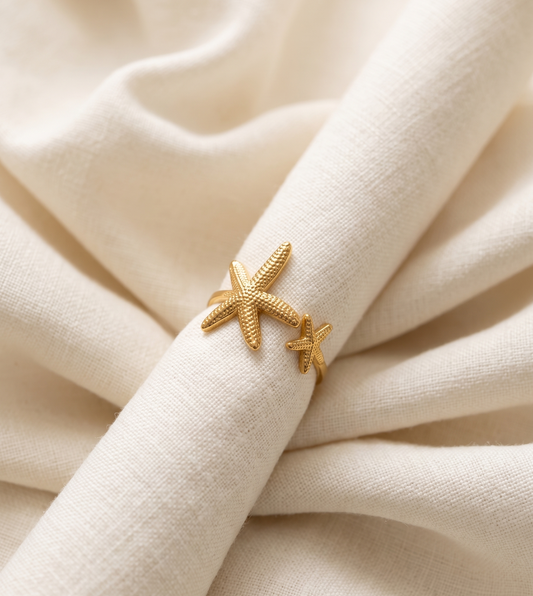 Gold starfish-shaped ring on a beige fabric background